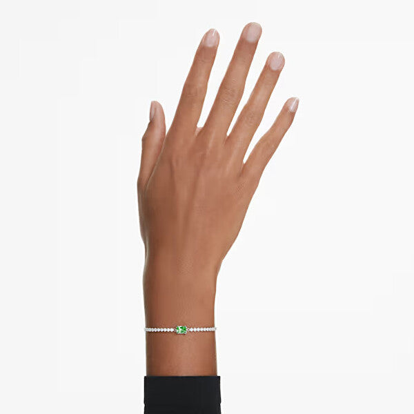 Elegant arm wearing delicate bracelet with green gemstone and pearls.