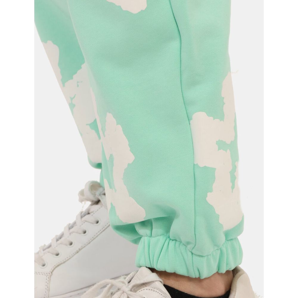 Close-up of Comme Des Fuckdown Green Cotton Jeans & Pant with unique print details and elasticated cuff, paired with white sneakers.